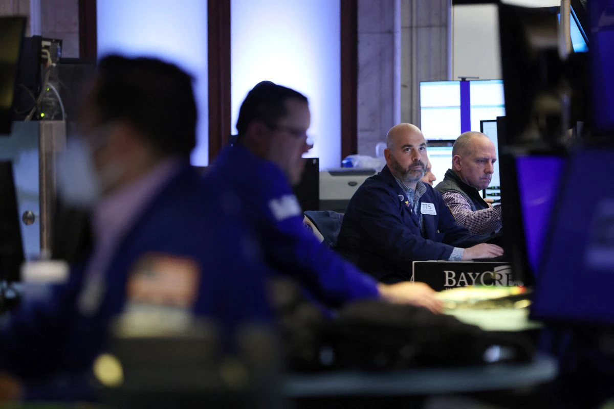 FILE PHOTO - Traders work on the trading floor at the New York Stock Exchange (NYSE) in Manhattan, New York City